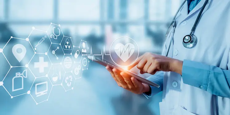 Ein Arzt in einem weißen Kittel mit Stethoskop bedient ein Tablet. Vor ihm schweben vernetzte hexagonale Symbole und ein Herzfrequenz-Symbol, die digitale Patientenüberwachung darstellen.