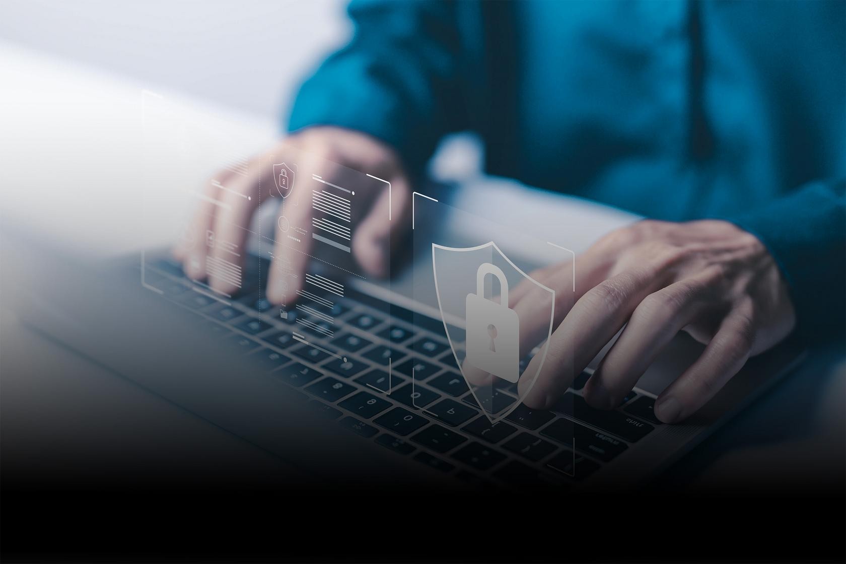 Eine Nahaufnahme von Händen, die auf einer Laptop-Tastatur tippen. Über den Händen schwebt ein futuristisches Overlay, das ein digitales Vorhängeschloss innerhalb eines Schild-Umrisses zeigt, flankiert von Linien und Datenpunkten, die Datensicherheit und Verschlüsselung symbolisieren.