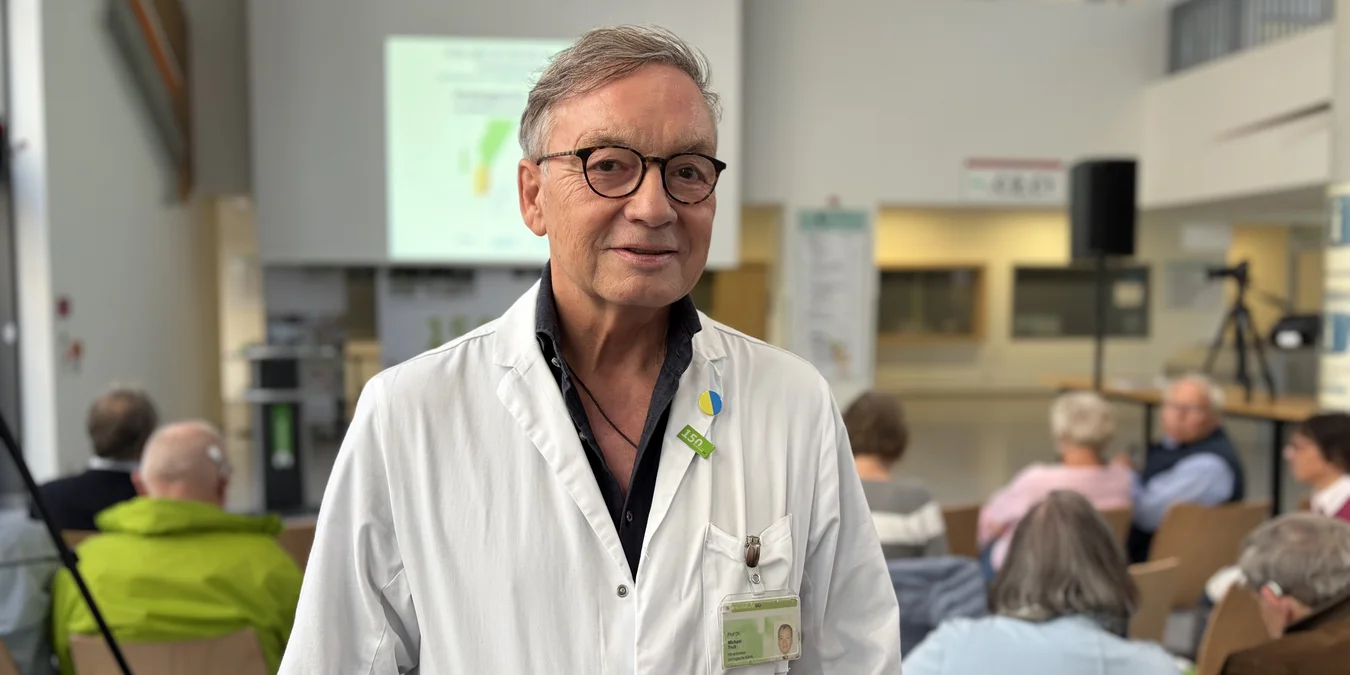 Portrait einer Person im weißen Kittel in einem Hörsaal